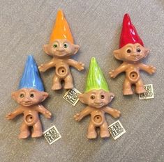 four small plastic troll dolls with tags on them