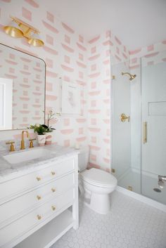 a white bathroom with pink and gold wallpaper