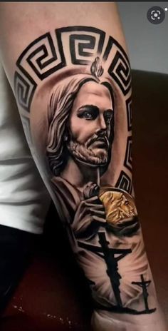 a man's arm with a jesus holding a cross and a gold coin on it