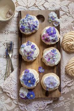 cupcakes decorated with edible flowers on a wooden board