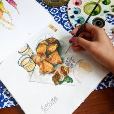 a person is painting food on paper with watercolors and paintbrushes next to them