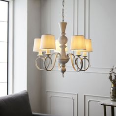 a chandelier with four lamps hanging from it's sides in a living room