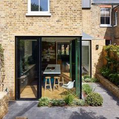 an outdoor dining area in front of a brick building with glass doors on the outside