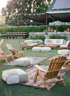 an outdoor seating area with lawn chairs and rugs on the grass, surrounded by string lights