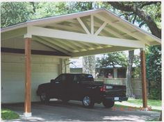 a black truck parked under a covered carport in front of a garage with a white roof