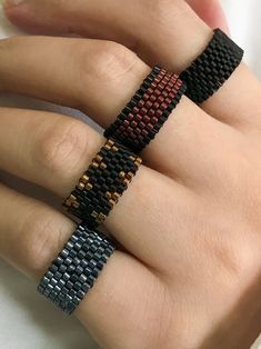 a woman's hand with two different colored rings on her fingers and one is wearing a ring made out of woven material