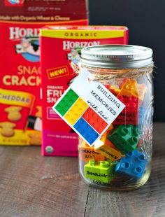 a jar filled with legos sitting on top of a wooden table next to boxes