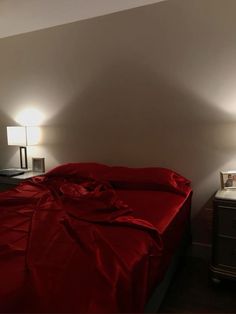 a bed with a red comforter and two lamps