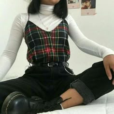 a woman sitting on top of a bed with her legs crossed and wearing black boots