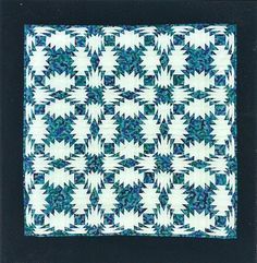 a blue and white quilt on display in a black frame with an image of a star pattern