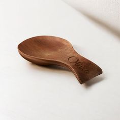 a wooden spoon sitting on top of a white table next to a wall and the word ousa written in cursive writing