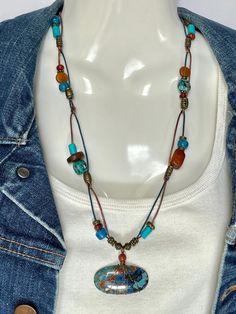 Shattuckite and Chrysocolla Cabochon wire wrapped with a Carnelian bead crown on bronze and turquoise 1mm leather cord. Mated with African Turquoise, Amber, Buffalo Bone, Carnelian, turquoise dyed bone, blue pony beads, and bronze metal beads. Bronze toggle to close. Cabochon is 1 5/8 x 3/4. Total necklace length is 24" with cabochon. No lead or nickel used. Please use the Last On, First Off approach. Stones discolor with lotions, perfumes, hairspray, sweat, chlorine, even some soaps, and will break if dropped. Casual Turquoise Beaded Necklaces For Festival, Multicolor Turquoise Necklace For Festival, Bohemian Chrysocolla Beaded Necklaces For Jewelry Making, Bohemian Chrysocolla Necklace, Bohemian Chrysocolla Beaded Necklace In Turquoise, Handmade Bohemian Turquoise Chrysocolla Necklace, Bohemian Blue Turquoise Chrysocolla Necklace, Bohemian Blue Chrysocolla Beaded Necklace, Bohemian Blue Chrysocolla Necklace