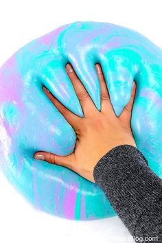 a person's hand on top of a blue and purple doughnut