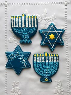 four decorated cookies with candles and stars on them are sitting on a white tablecloth