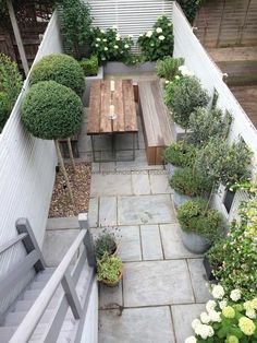 an outdoor dining area with potted plants and wooden table in the center, surrounded by white hydrangeas