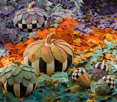 decorative pumpkins are displayed in front of colorful leaves