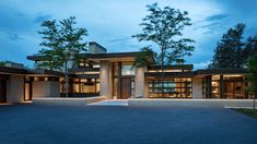 a large modern house with lots of windows and lights on it's front entrance