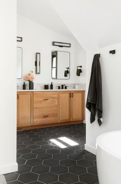 a bathroom with two sinks, mirrors and a bathtub