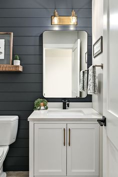 a white sink sitting under a bathroom mirror next to a toilet and counter top in a bathroom