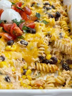 a casserole dish with pasta, black olives, tomatoes and sour cream