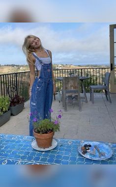 a woman standing on a patio next to a potted plant