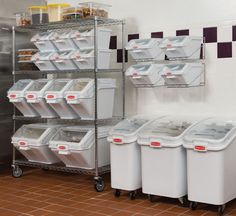 several bins and containers are stacked up in a storage area with tiled walls behind them