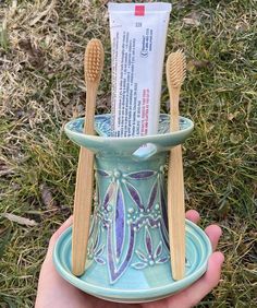 a toothbrush holder with two toothpaste tubes in it and some tooth paste on top