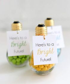 two small glass jars filled with yellow and green candies, one has a sign that says here's to a bright future