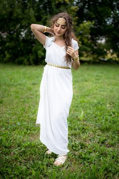 a woman in a white dress is standing on the grass with her hands behind her head