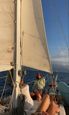 two people sitting on the front of a sailboat