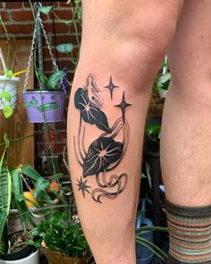 a man with a tattoo on his leg is standing next to a potted plant