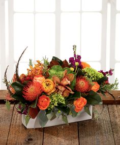 an arrangement of flowers in a white vase on a wooden table