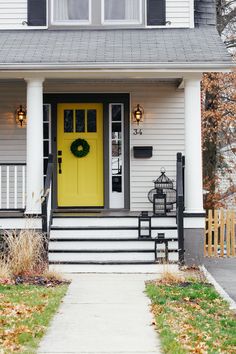 a yellow front door on a white house