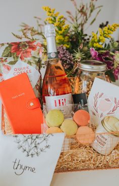 a basket filled with cookies and wine next to flowers