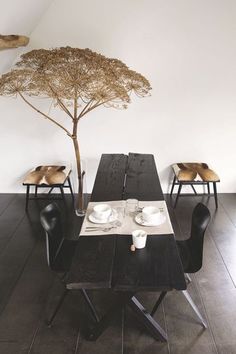 a table with two chairs and a tree in the corner on the wall behind it