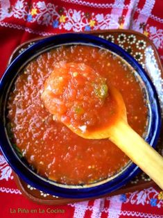 a wooden spoon in a blue bowl filled with red sauce