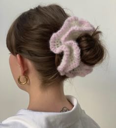 a woman wearing a pink and white crochet hair scrunch with gold hoop earrings