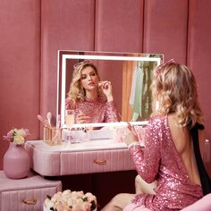 a woman sitting in front of a mirror looking at herself in the mirror while brushing her teeth