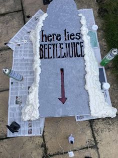 there is a sign that says here lies beetle juice on the ground with other items around it