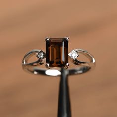 It is a natural smoky quartz ring. The main stone is 6 mm*8 mm emerald cut.weight about 1.43 carats. The basic metal is sterling silver and plated with rhodium. To change the metal to a solid gold (white/rose) or platinum is also available, please ask for a quotation if you want. You can also go to my shop Home for more elegant rings: https://www.etsy.com/shop/godjewelry?ref=hdr_shop_menu More smoky quartz rings: https://www.etsy.com/shop/godjewelry?ref=seller-platform-mcnav&section_id=22545 Quartz Rings, Elegant Rings, Black Diamond Solitaire, Brown Rings, Swiss Blue Topaz Ring, Wedding Ring For Women, Silver Wedding Ring, Ring Emerald Cut, Green Amethyst Ring