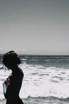 a woman standing on top of a beach next to the ocean