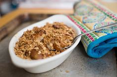 a white bowl filled with granola next to a blue bottle