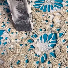 a piece of crocheted material is laying on top of a blue table cloth