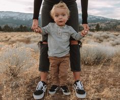 a woman holding the hands of a small child who is standing on his mother's lap