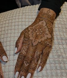 two hands with henna designs on them sitting on a bed next to each other