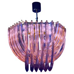 a pink chandelier hanging from a ceiling fixture with glass rods and metal fittings