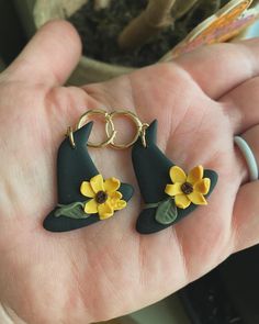 a person is holding two flower earrings in their hand