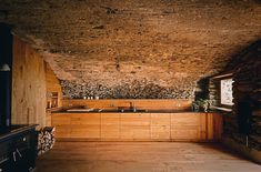 a kitchen area with wooden cabinets and stone walls, along with a wood stove top oven