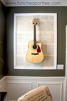 an acoustic guitar mounted to the side of a wall with music sheets in front of it