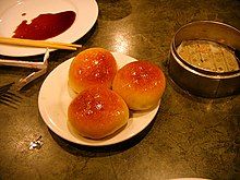 three rolls sitting on a plate with dipping sauce next to it and a bowl of soup